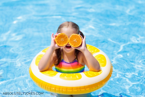 little girl in swimming pool with inflatable toy and orange slices